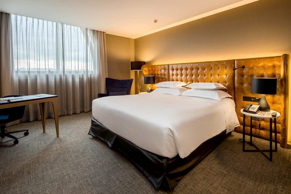 Alternativa de descanso ao lado do aeroporto - quarto hotel Pullman São Paulo - cabeceira em couro caramelo, roupa de cama branca e decor clean